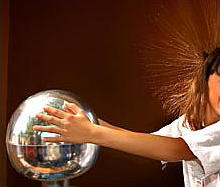 a woman's hair blows completely with fixed when she touches a Van de Graaff generator